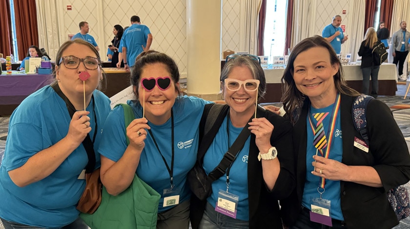 Four staff members posing together and holding props