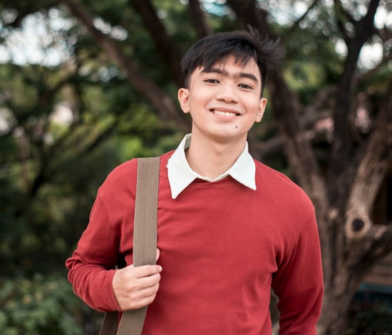 Online high school student with backpack smiling outside