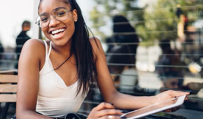 Young teen smiling in a white shirt holding a notebook