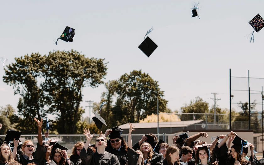 Willamette Connections Academy Class of 2023 throw their black caps into the air.